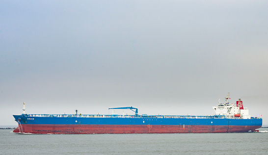 Rotterdam, The Netherlands - June 10, 2014: Large oil tanker ship Bravo leaving the port of Rotterdam on an overcast day. The Port of Rotterdam is the largest port in Europe and one of the world's largest container ports located in the city of Rotterdam, Netherlands.