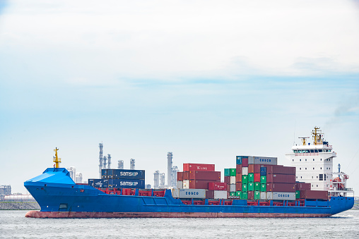 Cargo ship with containers leaves the port of Rotterdam on a sunny day. The Port of Rotterdam is the largest port in Europe and one of the world's largest container ports located in the city of Rotterdam, Netherlands.