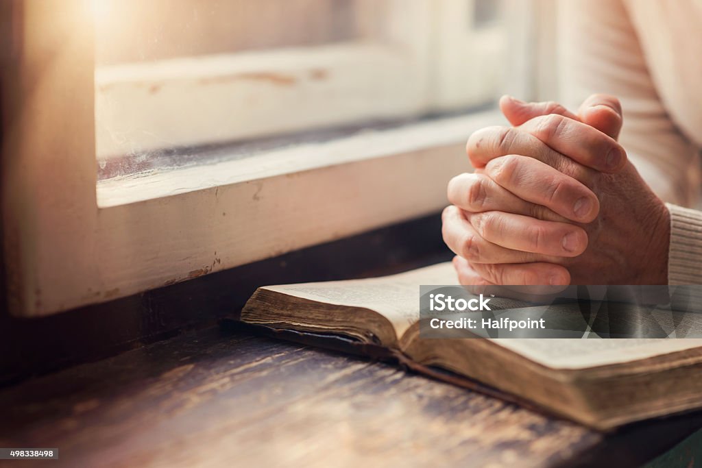 Woman with Bible Hands of an unrecognizable woman with Bible praying Praying Stock Photo
