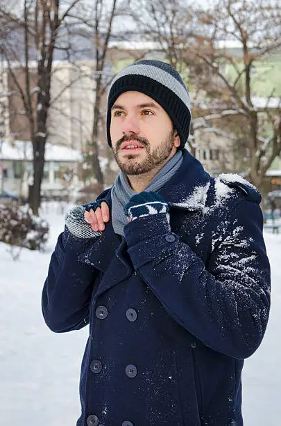 Photo of Young man in a coat covered with snow