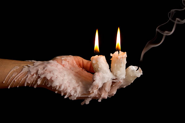 Three candle sticks on fingers buring smoulder stock photo