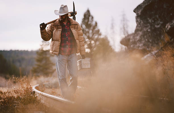 istock Working Man walks along overgrown rustic railroad tracks carrying tools 498365249
