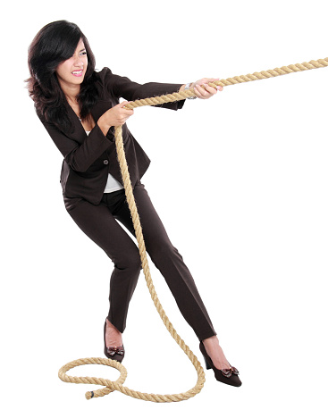 Business competition. Young business woman pulling a rope isolated on white background