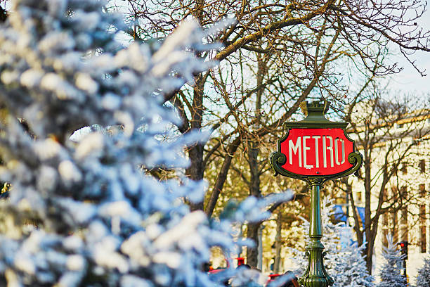 Parisian metro sign with trees covered with snow