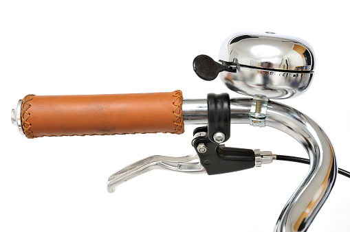 Close up of a silver bicycle bell and leather handgrip