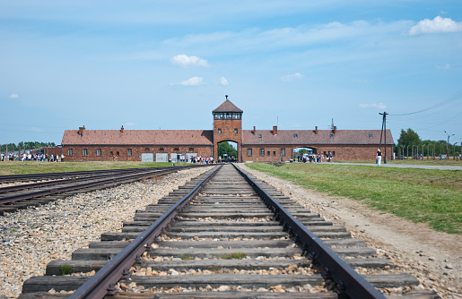 Oświęcim, Poland - June 05, 2019: Electric fence with barbed wire and brick prison buildings at the Auschwitz-Birkenau concentration camp in Oświęcim, Poland. Europe.
