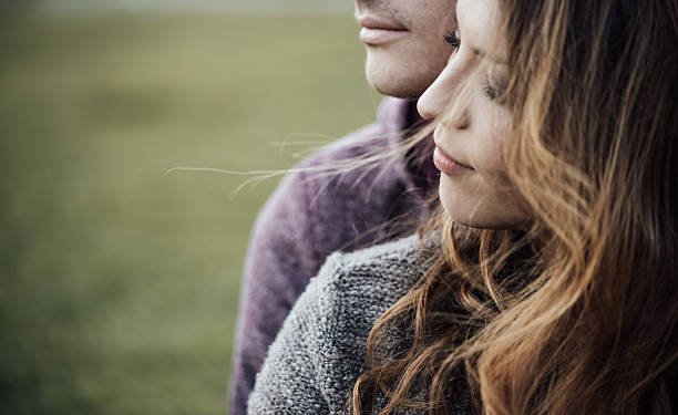 Young loving couple sitting on the grass Young loving couple outdoors sitting on grass, hugging and looking away, future and relationships concept teen romance stock pictures, royalty-free photos & images