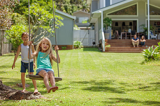 family playing outdoors Family watches the kids as they swing in their backyard tree swing. bondi beach photos stock pictures, royalty-free photos & images