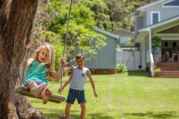 istock brother and sister playing on the swing 498377828