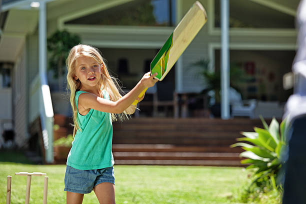 girl batting at cricket Kids playing cricket in their backyard. batting sports activity stock pictures, royalty-free photos & images