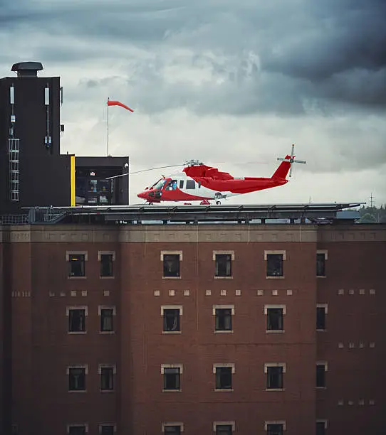An emergency services helicopter sits on the helipad of a city hospital.