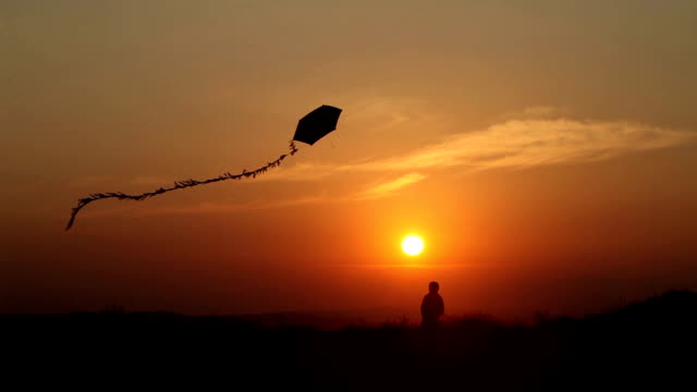 Little Boy Flying A Kite at Sunset