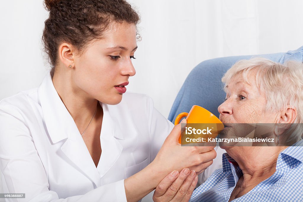 Nurse gives drinking old woman Nurse gives something to drink old woman Adult Stock Photo