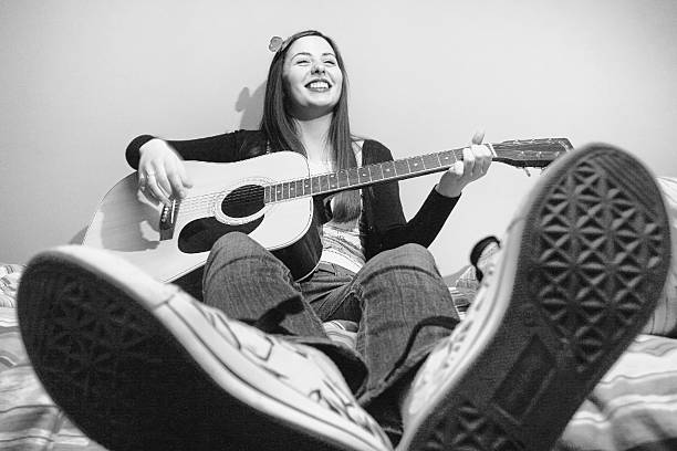 istock Young brunette playing guitar on bed black and white 498389313