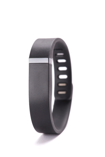 Antibes, France - June 18, 2014: Fitbit Flex activity and sleep tracking wristband, in black. The tracker is intended to help the wearer attain a more healthy and active lifestyle. Bluetooth wireless technology is used to communicate logged data to smartphone or computer for analysis, and the device can also function as a silent, vibrating alarm clock.