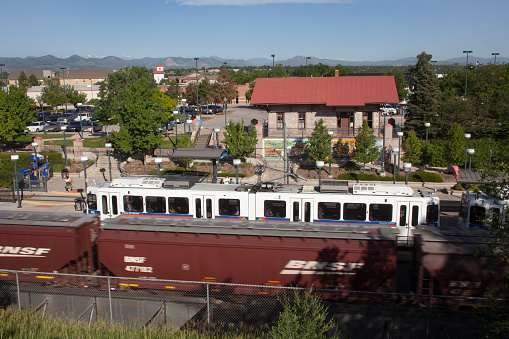 Littleton, Colorado, USA - June 13, 2014: A northbound RTD light rail train picks up passengers as a BNSF freight train rolls by the Littleton Station.