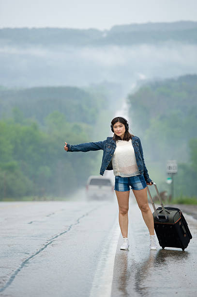 istock Woman standing on road waiting with her suitcase. 498401585