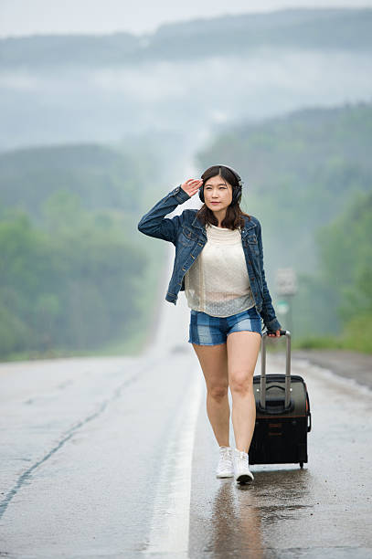 istock Woman standing on road waiting with her suitcase. 498401589