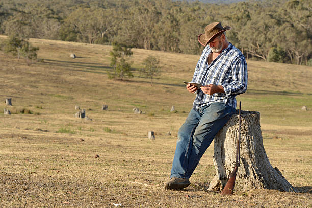 Australian Farmer using Tablet Farmer in the Bendigo region, enjoying the evening light, using a tablet for communication. bendigo photos stock pictures, royalty-free photos & images