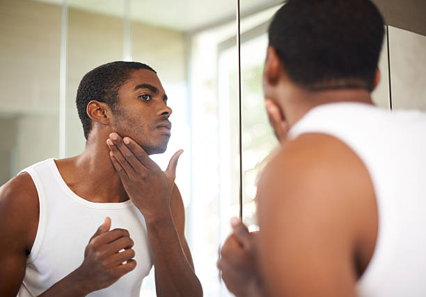 Looking sharp! Shot of a handsome young man applying moisturizer to his face cologne photos stock pictures, royalty-free photos & images