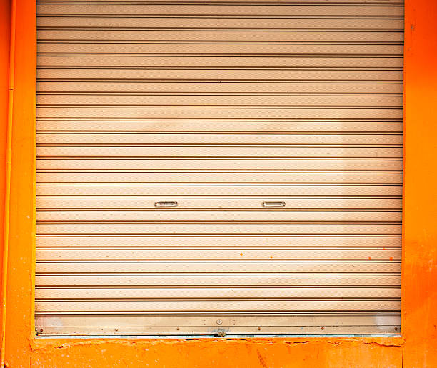 istock Shuttered roll up metal door with orange wall 498404397