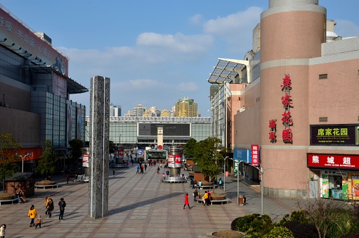 Shanghai, China - February 16, 2013: The courtyard leading to the main entrance to Shanghai Railway station. Commercial establishments, including restaurants and shops can be seen in the photo. Also, a metal sculpture 'public art' is located in the square. Train travel is still popular and common with most Chinese as the rail network reaches most parts of the country. Recently, the authorities have invested large amounts of money upgrading the rail network, including introducing 'bullet' trains between major routes such as Shanghai - Beijing. 