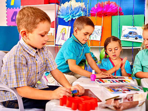 istock Kids holding colored paper on table in kindergarten 498405606