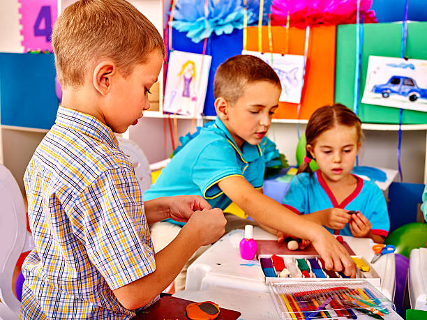 istock Kids holding colored paper on table in kindergarten 498405640