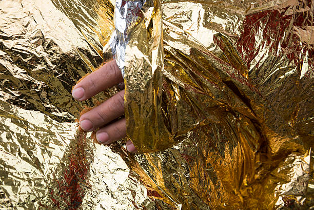 Close-up of an Afghan refugee's hand sticking out from a foil blanket in the port of Mytilene on the Greek island of Lesbos