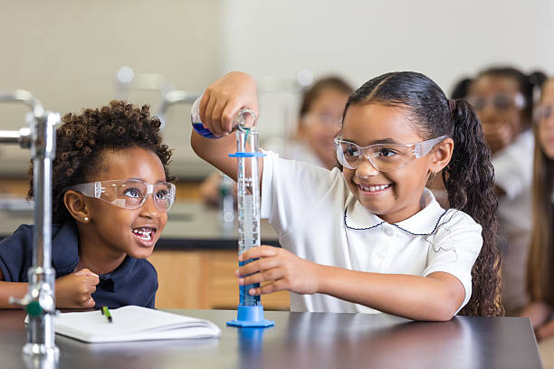 istock Cute elementary school girls using chemistry set in science class 498422771