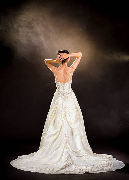 Bride in champagne wedding dress on dark background 