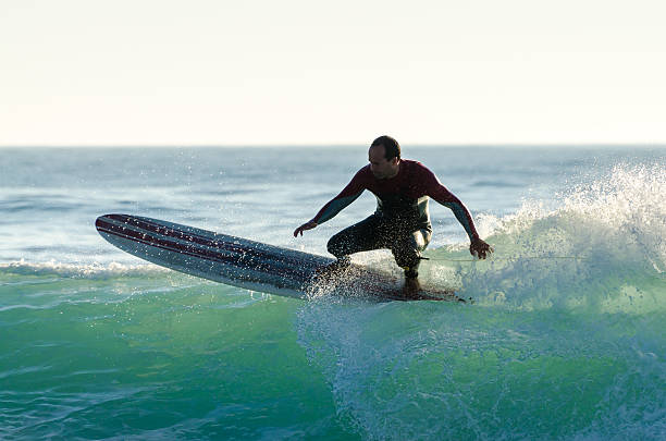 istock Long boarder surfing the waves at sunset 498424431