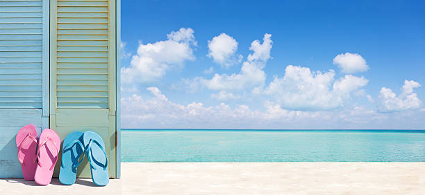 istock Tropical Paradise Beach Vacation with Flip-flops Couple Panoramic Banner Ad 498424523