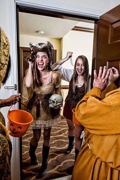Two young adult women surprise a couple with knives during Halloween.