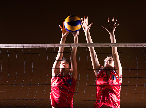 Two female volleyball players on the net.   