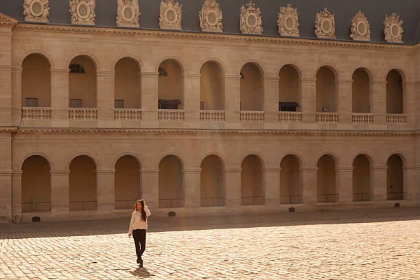 Young woman walking across the courtyard of Invalides in Paris, France.  