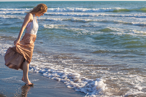 Young girl soaking her feet in the ocean.