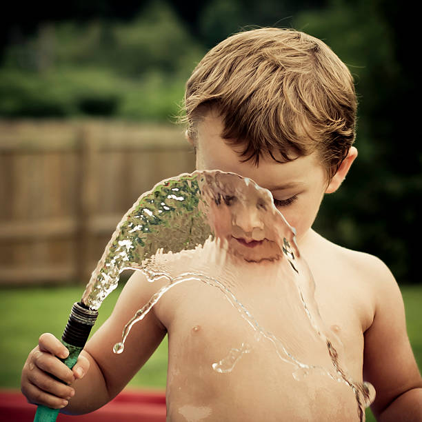 istock Boy plays with water hose outdoors 498429027