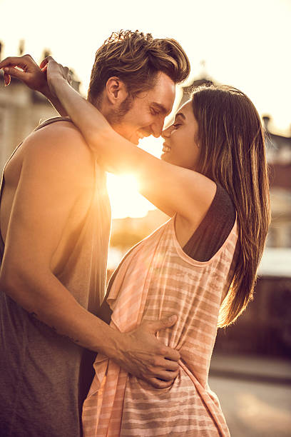 junge romantisches paar umarmt auf der straße bei sonnenuntergang. - face to face twilight togetherness vertical stock-fotos und bilder