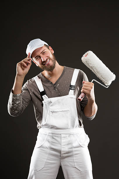 Attractive bearded young painter with paint roller stock photo
