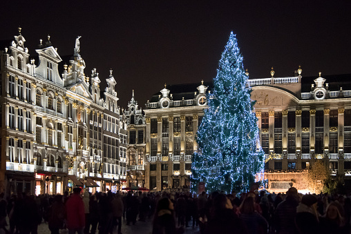 Night view of the crowded christmas market at Grand Place in Brussels, Belgium. Illuminated gothic buildings and christmas tree.