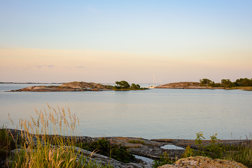 Sunset light over small skerries and sailboats moored at a small rocky island in the outer part of the archipelago of Stockholm, Sweden