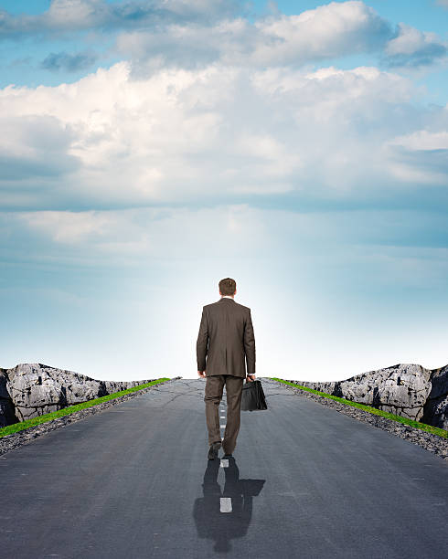 istock Businessman on road with mountains, rear view 498433240