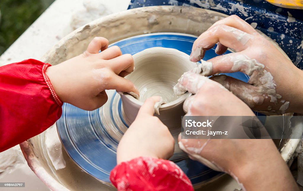 Teaching pottery A Craftwoman's hands guiding a child hands, to teach him to work with the ceramic wheel. Child Stock Photo
