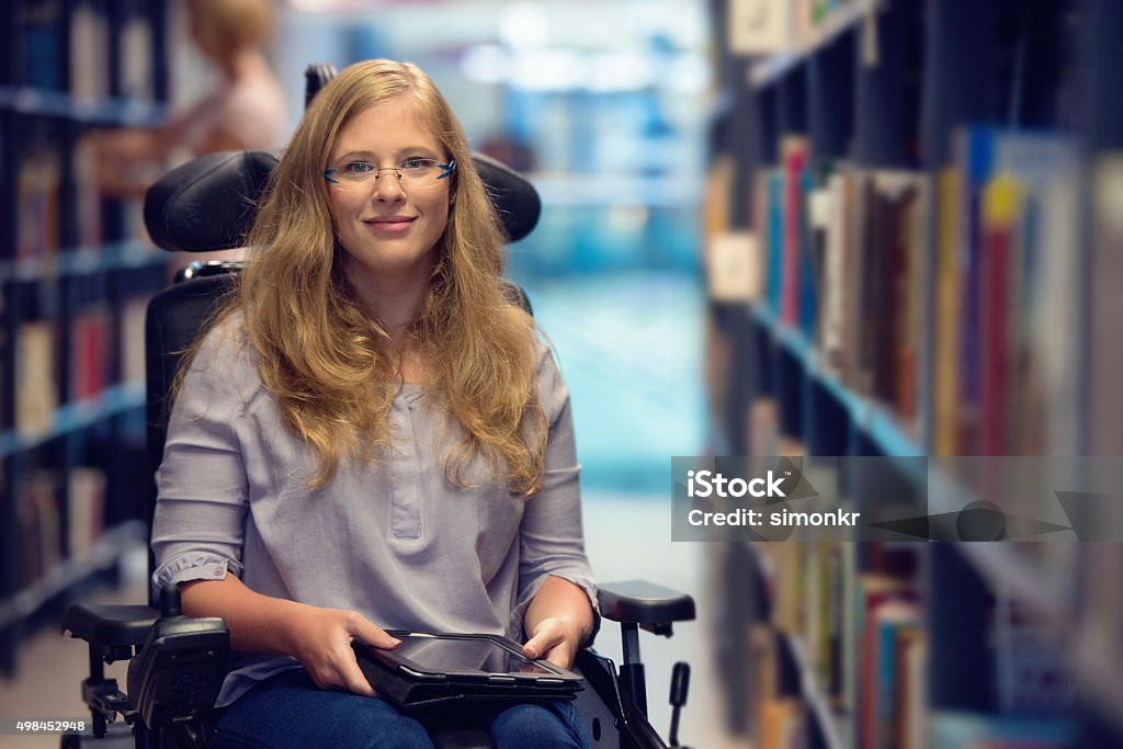 Porträt der jungen Frau im Rollstuhl in der Bibliothek - Lizenzfrei Rollstuhl Stock-Foto