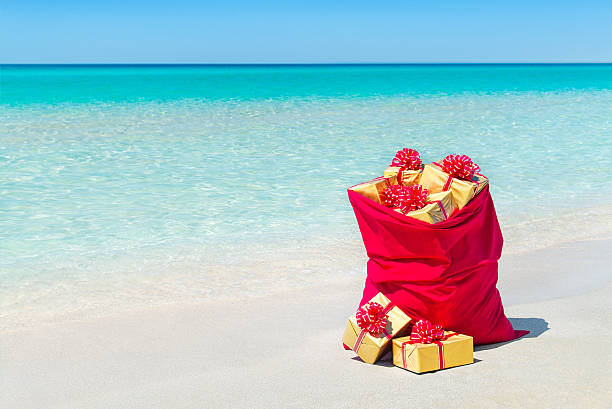 istock Christmas sack full of wrapped gift boxes at tropical beach 498455996
