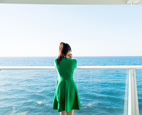 Asian woman standing near railings on cruise
