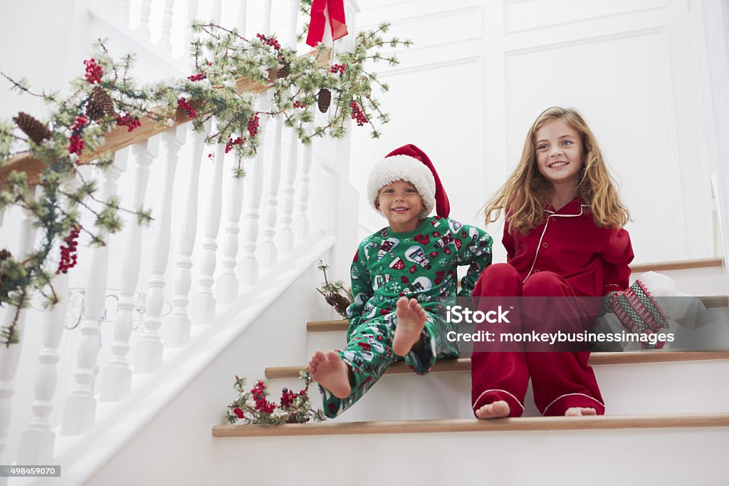 Two Children Sitting On Stairs In Pajamas At Christmas Christmas Stock Photo