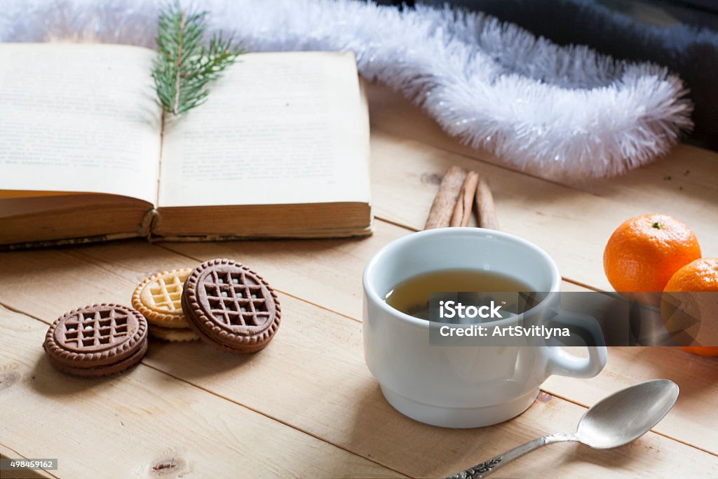 Cup of hot tea with books on wooden table. Cup of hot tea with books, cookies and tangerines on light wooden table. 2015 Stock Photo