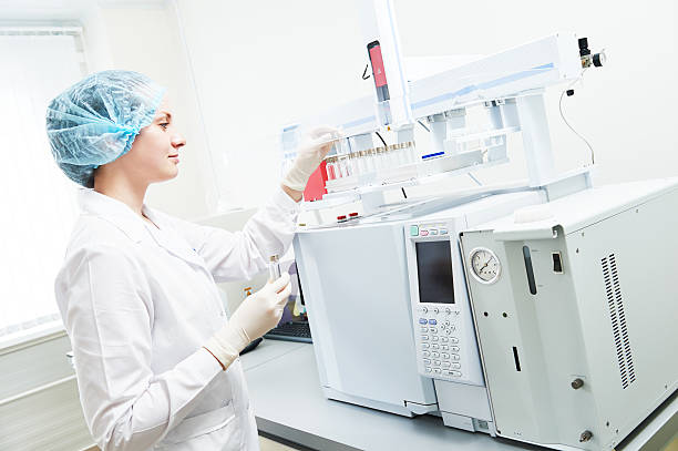Female scientific researcher putting flask in Gas Chromatography Pharmacy and chemistry theme. Female scientific researcher putting flask with liquid solution in gas chromatography  chromatography stock pictures, royalty-free photos & images